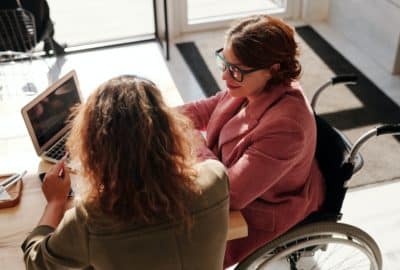 Two women looking at a computer screen. Featured image for podcast episode "Why do research on research?"